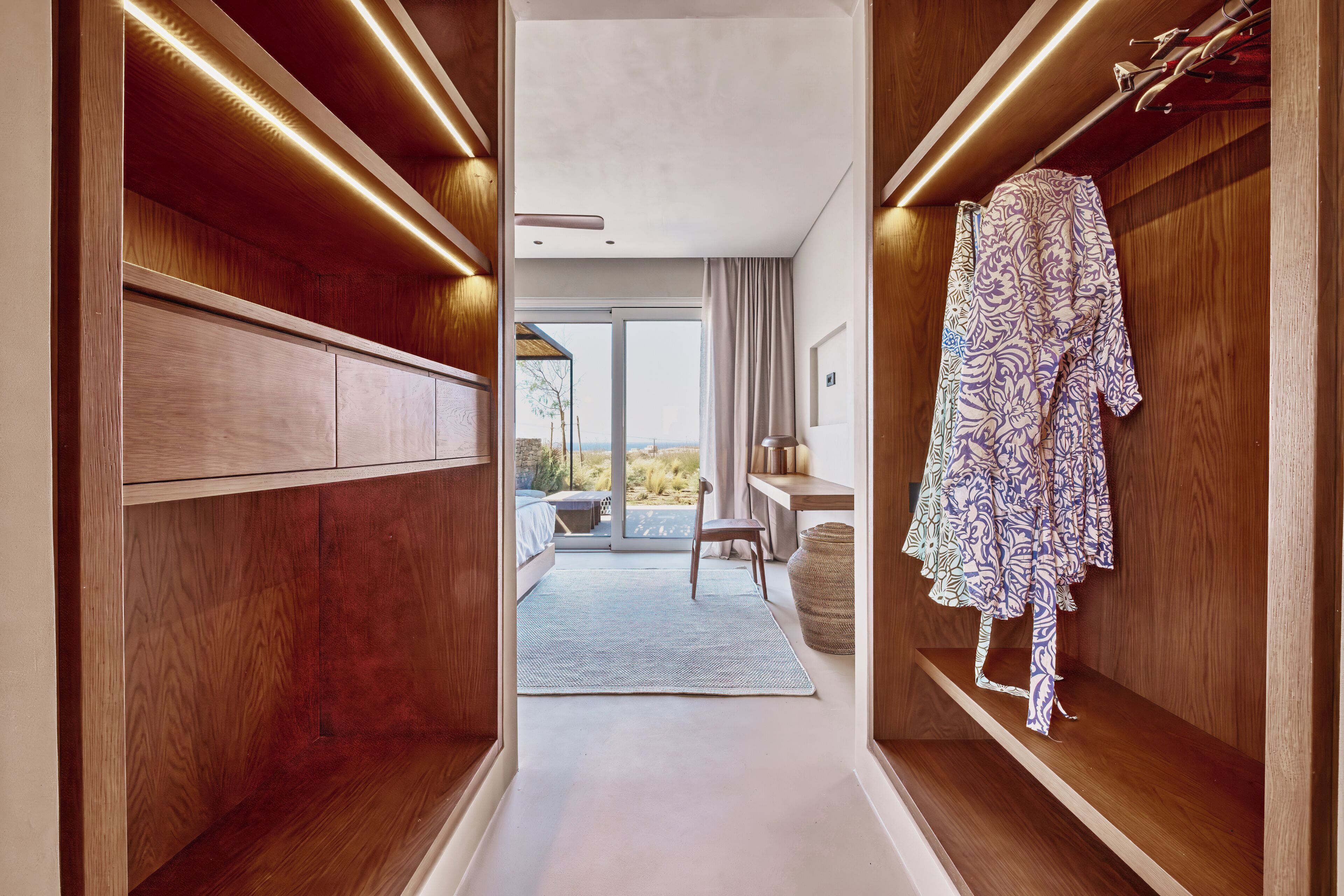 A hallway with wooden paneling, a bench, and a robe hanging on a shelf.