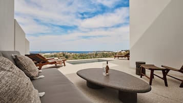 Un espacio al aire libre moderno con una mesa de piedra, sillones reclinables y un sofá.