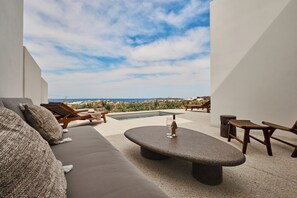 A modern outdoor seating area with a stone table, lounge chairs, and a sofa.