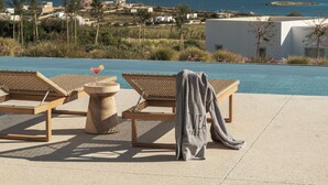Un espace aménagé au bord de la piscine, avec des chaises longues, une boisson et une serviette.