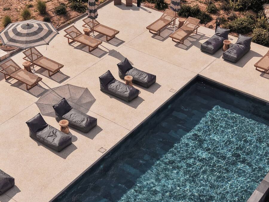 Un área de piscina con sillones de descanso y sombrillas.