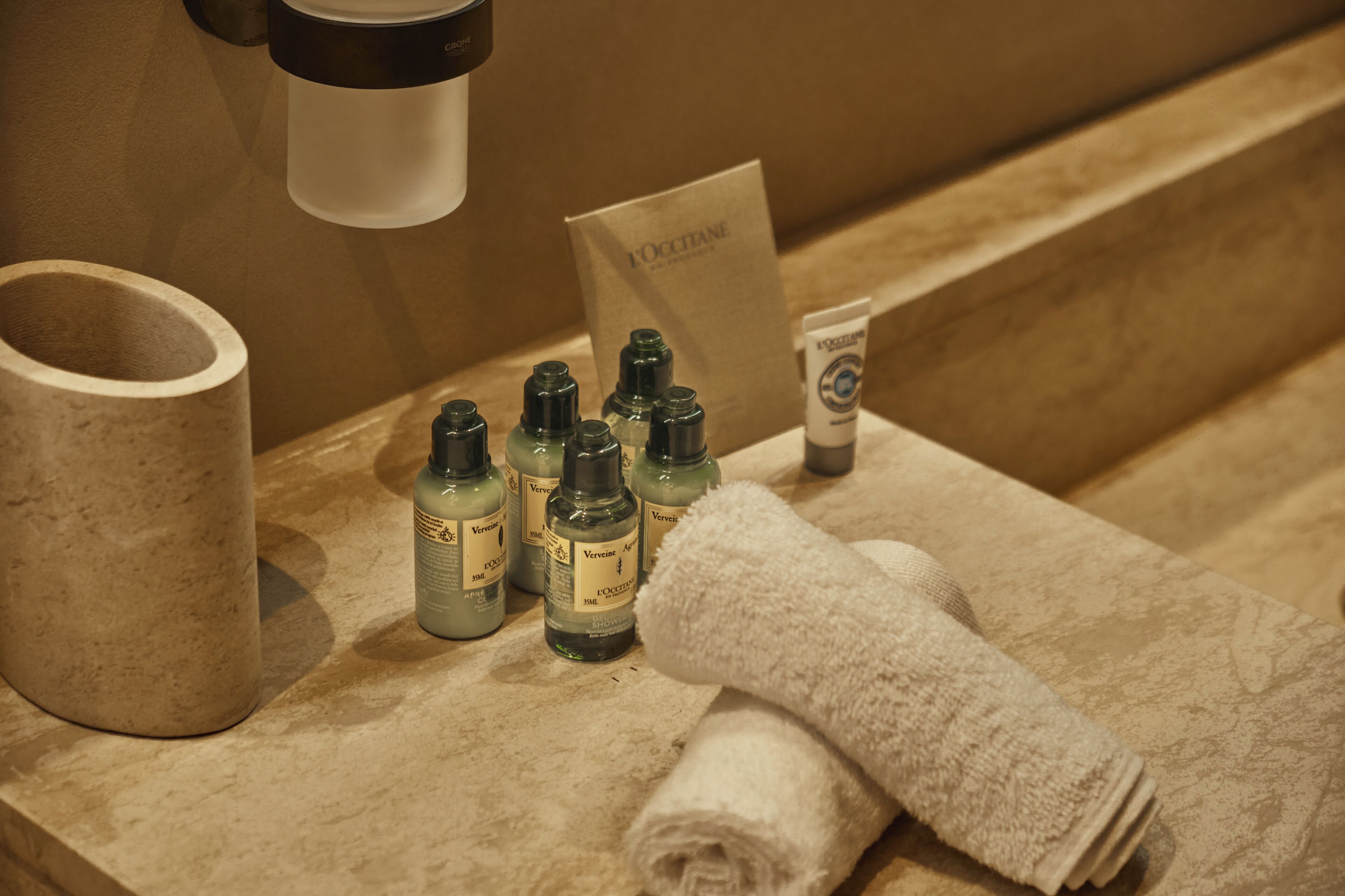 A bathroom counter with toiletries, a towel, and a paper bag.