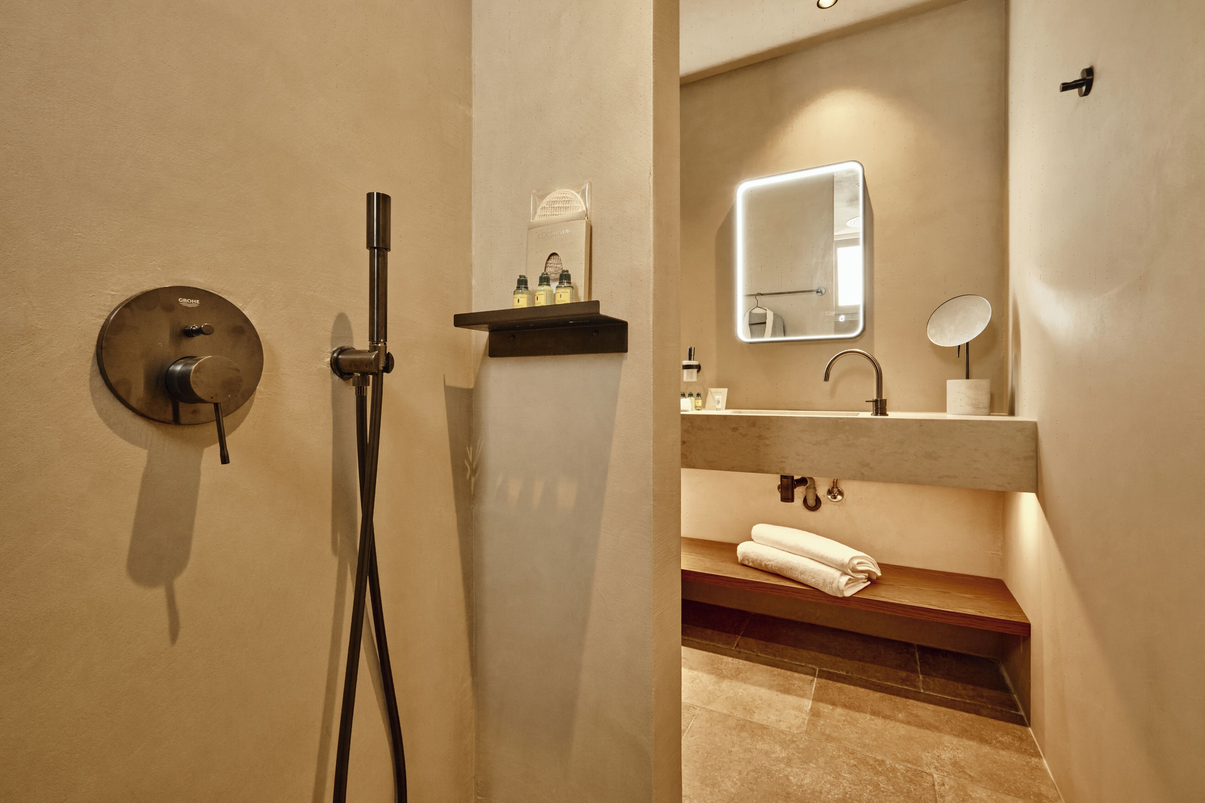 Un baño con ducha, un lavabo con espejo y un perchero para toallas.