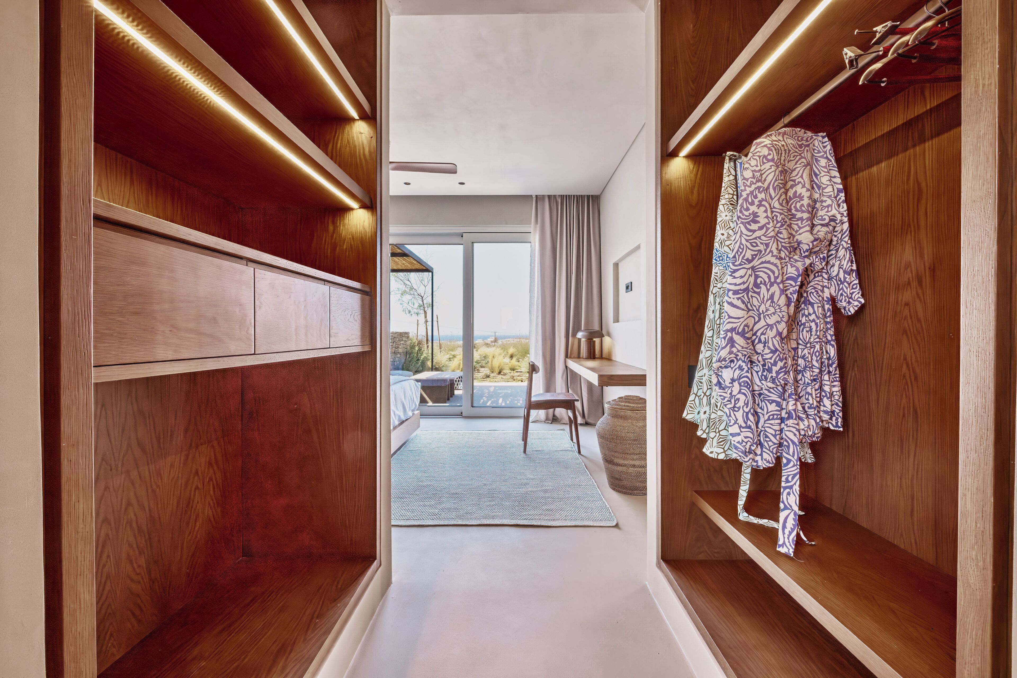 A hallway with wooden paneling, a bench, and a robe hanging on a shelf.
