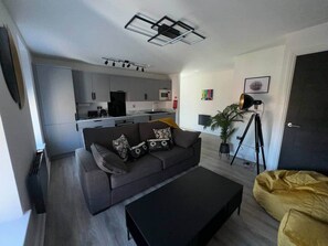A modern living room with a sofa, coffee table, and a kitchen area in the background. - Apt 5, 38 Everton Road (Liverpool)