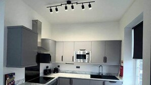 Een moderne keuken met grijze kastjes, een centraal eiland, een inbouwoven en een magnetron.
