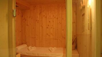 A wooden cabin room with a bed, a bench, and a small table.