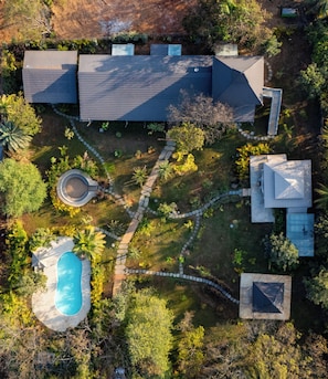 Vista aérea de una propiedad residencial con piscina, senderos en el jardín y varias construcciones.