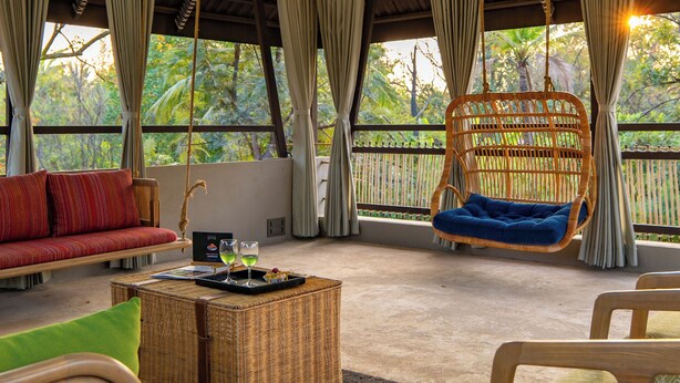 Una habitación amplia con techo alto, muebles de mimbre y una silla colgante.