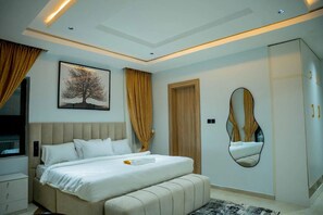 A modern bedroom with a bed, a wardrobe, a mirror, and a painting on the wall. - Wanderluxe Shortlets (Abuja)