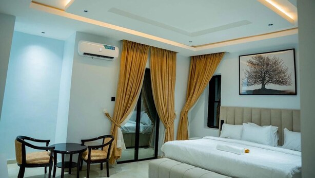 Une chambre d’hôtel moderne équipée d’un lit, d’un bureau avec deux chaises, d’une fenêtre avec des rideaux et d’un climatiseur fixé au mur.