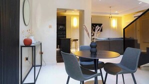 Un salon moderne avec une table ronde, des fauteuils gris, un canapé et un escalier.