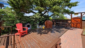 A wooden deck with a red chair, a barbecue grill, and a covered seating area. - The Lemon Twist at Carolina Beach (Carolina Beach)