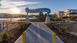 A pathway leading to Brandy Myers Memorial Playground with a clear sky and sun setting in the background. - The Lemon Twist at Carolina Beach (Carolina Beach)