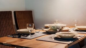 Una mesa de comedor dispuesta con platos, vasos y un bol.