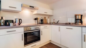 Una cocina moderna con armarios blancos, electrodomésticos de acero inoxidable y una cafetera.