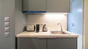 A compact kitchenette with a built-in toaster, kettle, and sink. - Athena Urban Retreat Apartment (Athens)