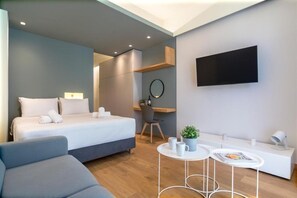 A modern hotel room with a bed, a desk, a chair, a small table with two cups, and a TV mounted on the wall. - Athena Urban Retreat Apartment (Athens)