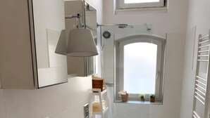 A modern bathroom with a large mirror, a sink, a shower, and a window. - Apartment Stella – Elegant Historic Apartment in the City Center (Kassel)