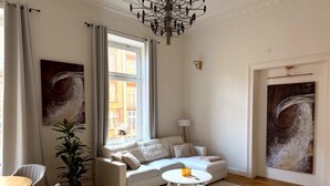 A modern living room with a sofa, a round coffee table, a dining area with chairs, a potted plant, and artwork on the walls. - Apartment Stella – Elegant Historic Apartment in the City Center (Kassel)