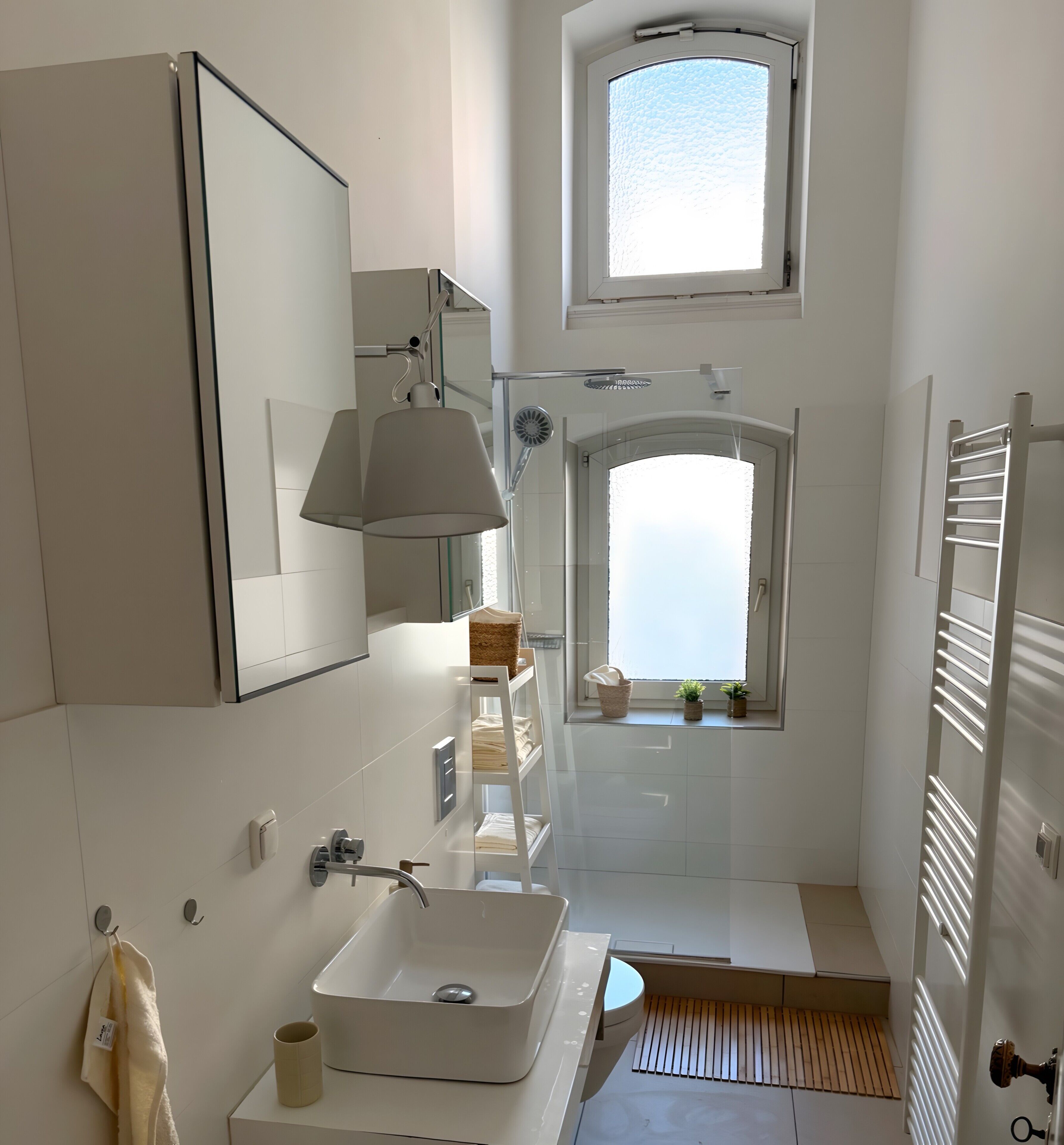 A modern bathroom with a large window, a built-in shower, a sink, and a towel rack.