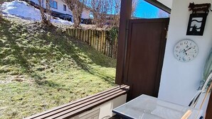 A covered outdoor seating area with a view of a house and a clock on the wall. - Apartment 'Älple' with Private Terrace and Wi-Fi (Bad Hindelang)