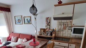 A compact living space with a dining table, chairs, a sofa, a kitchen area, and a ceiling light fixture. - Apartment 'Älple' with Private Terrace and Wi-Fi (Bad Hindelang)