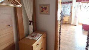 A room with a wooden dresser, a small table, a wall-mounted picture, and a doorway leading to another room. - Apartment 'Älple' with Private Terrace and Wi-Fi (Bad Hindelang)
