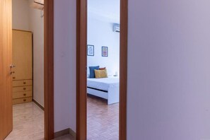 Une chambre à coucher comprenant un lit, une armoire et une porte donnant sur une autre pièce.