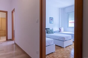 Une chambre avec deux lits, un plancher en bois et une fenêtre avec des stores.
