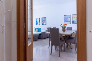 Un intérieur moderne comprenant un coin repas, des canapés et des œuvres d’art abstrait accrochées aux murs.