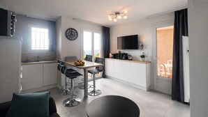 Une cuisine moderne avec un coin repas, un téléviseur à écran plat et une vue sur l’extérieur.