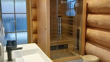 L’intérieur d’un chalet en bois comprend un sauna vitré, un évier blanc et un banc en bois.