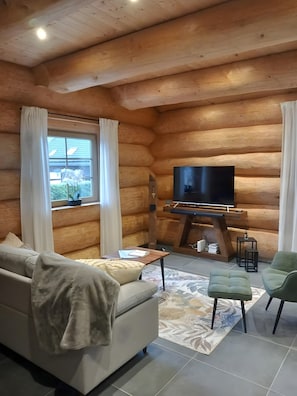 A log cabin interior with a sofa, a television, and a small table.