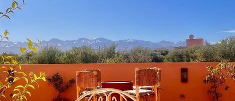 A terrace with a table, chairs, and a view of mountains.