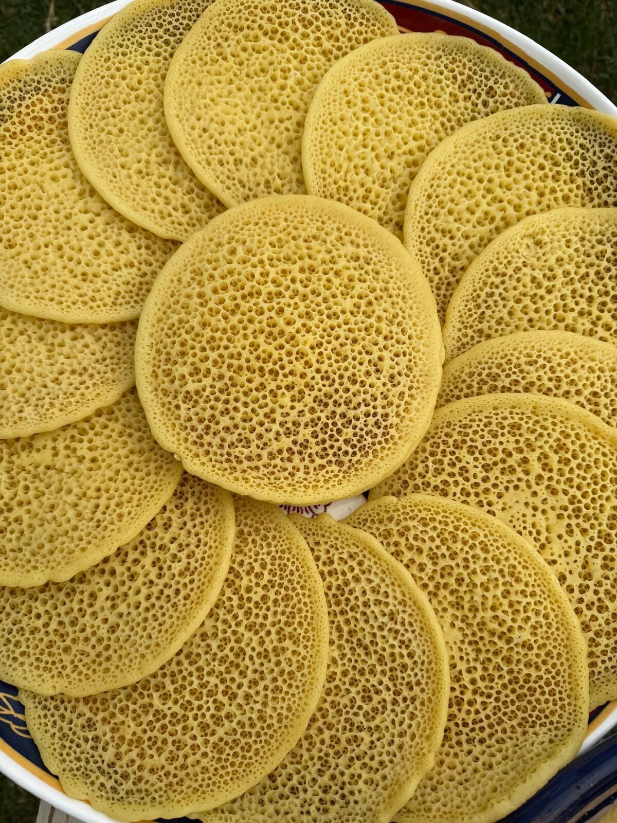 A bowl of round, golden-brown pancakes with a honeycomb texture.