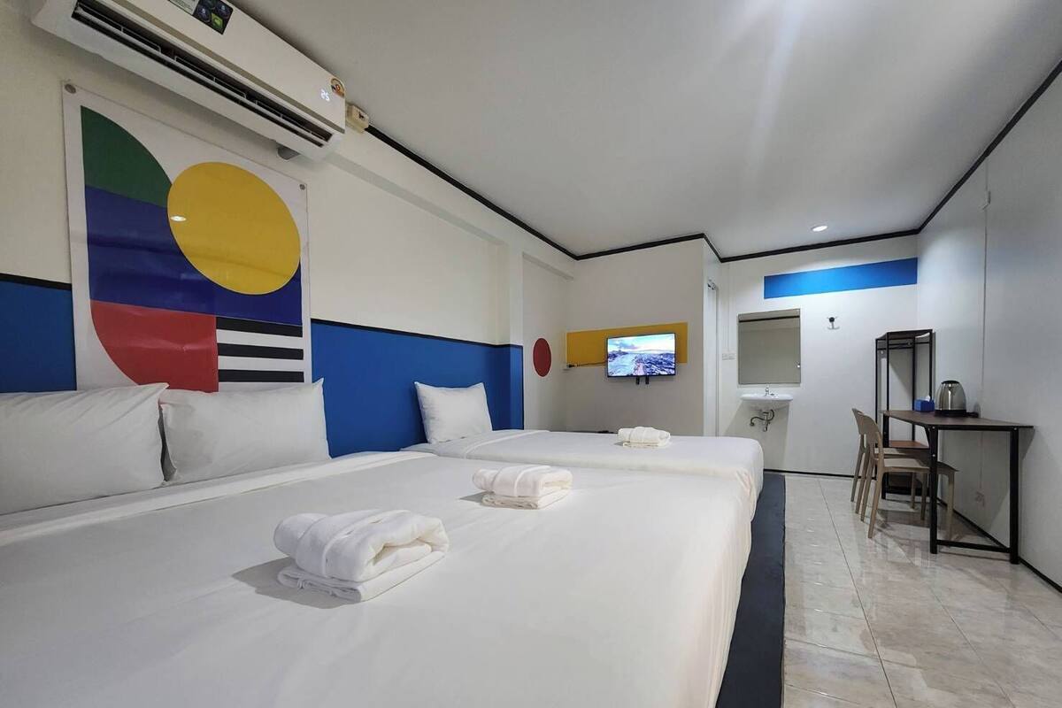 Una habitación de hotel con dos camas, televisión, escritorio y baño.