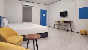 Una habitación de hotel con cama, escritorio, silla, televisor y una mesita.