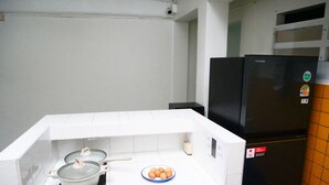 Una cocina con baldosas blancas, una estufa con una olla, un plato con huevos y un refrigerador negro.