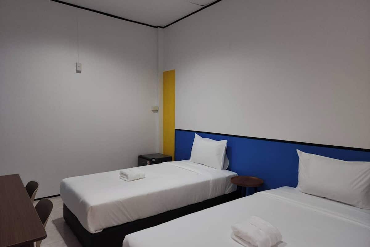 Habitación de hotel con dos camas, un escritorio y una silla.