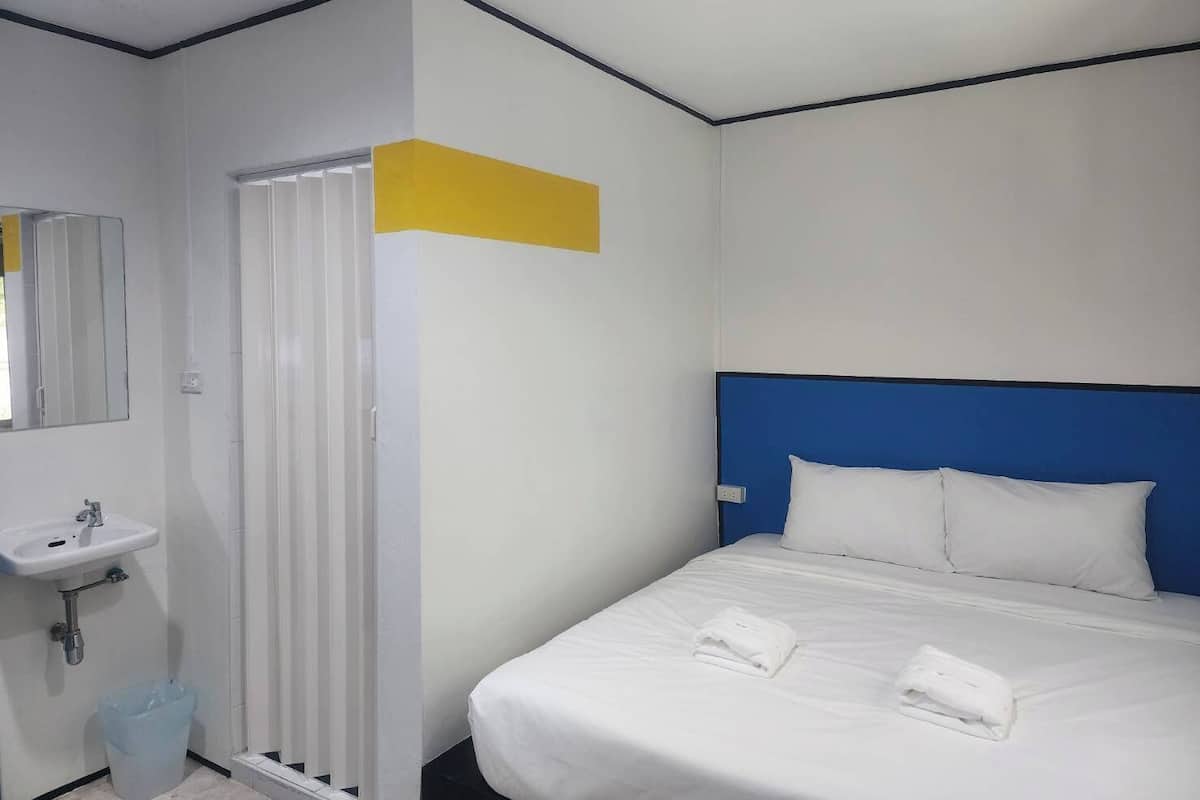 Una habitación de hotel con una cama, un lavabo blanco y un espejo.