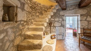 A stone staircase leading to a room with a wooden bench, a small table with books, and a rustic interior.