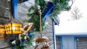 A wooden building with a blue roof, a hanging Christmas garland, and a lantern on the wall. - Nice Cozy Cottage With Fireplace, Barbecue hut and Wood Sauna (Jädraås)