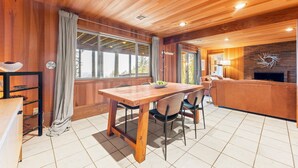 Een houten interieur met een eettafel, stoelen, een bank en een open haard.