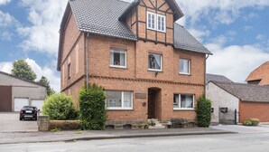 A two-story house with a brick facade, a gabled roof, and a front entrance with steps. - Apartment 'Hofhausnr3' with Private Terrace, Garden, and Wi-Fi (Warburg)