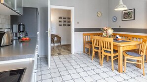 A modern kitchen with a coffee maker, a dining table with chairs, and a hexagonal tiled floor. - Apartment 'Hofhausnr3' with Private Terrace, Garden, and Wi-Fi (Warburg)
