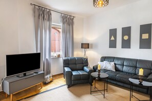 En moderne stue med et fladskærms TV, lædersofa og et lille sofabord.