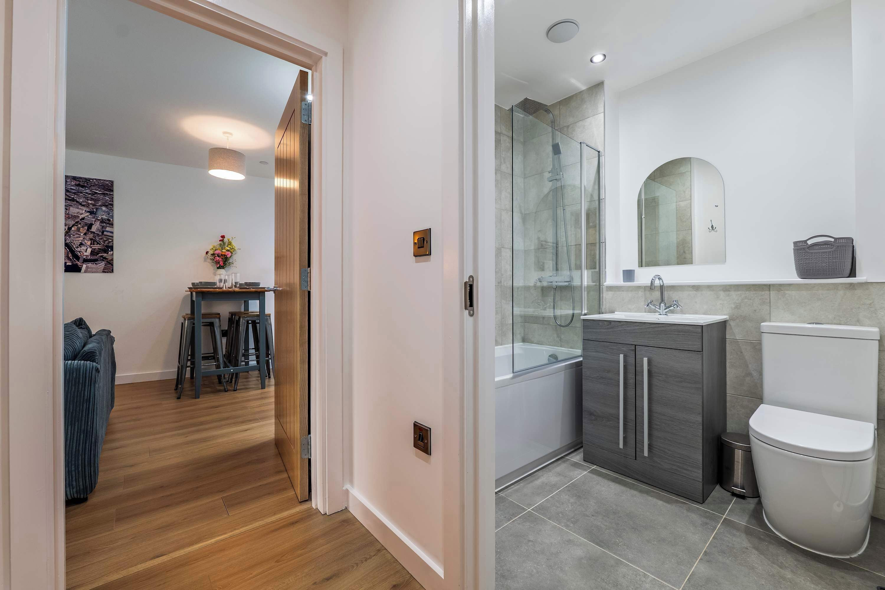 Une salle de bain moderne avec une douche à parois de verre, des toilettes blanches et un meuble-lavabo gris.