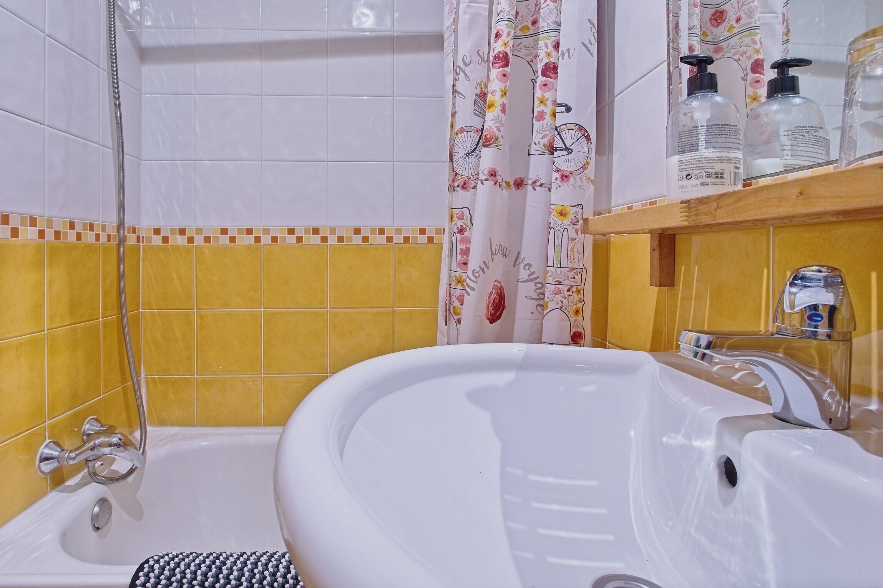 Un baño con bañera, ducha y un estante con artículos de aseo.