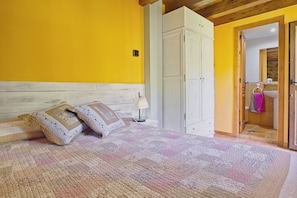 A bedroom with a bed, a nightstand, a lamp, a wardrobe, and a bathroom visible through an open door. - Country House 'Ribera Del Cantero' with Mountain View, Private Pool and Wi-Fi (Valdecañada)